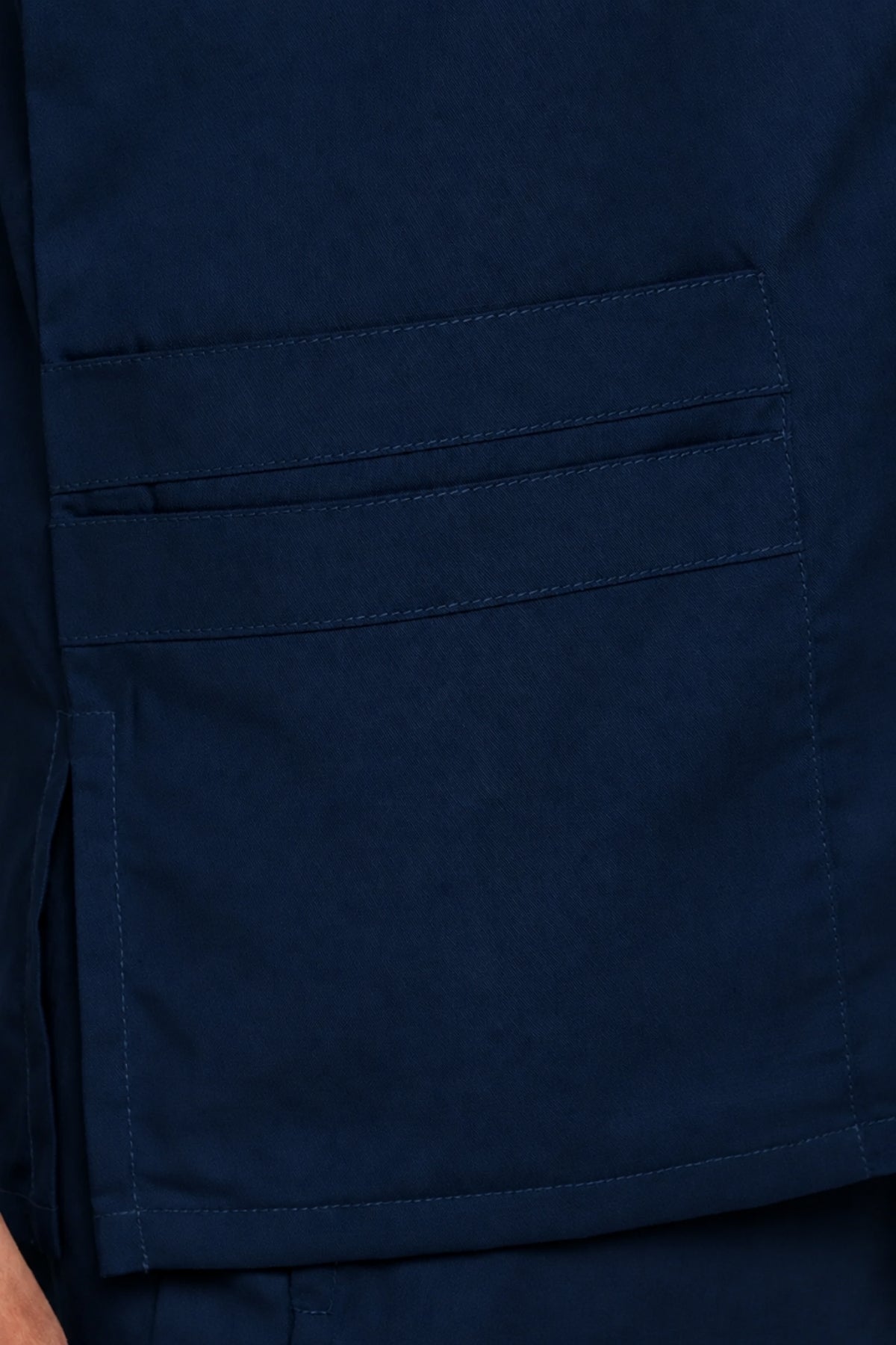 detailed view of the layered lower pocket and reinforced stitching on navy scrubs